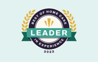 A circular emblem with a green ribbon displaying the text "LEADER" in white. The outer ring reads "BEST OF HOME CARE" at the top and "IN EXPERIENCE" at the bottom. The year "2022" is at the bottom, and wheat-like branches decoratively surround the emblem.