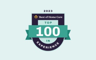 A badge with "2023" at the top, "Best of Home Care" below it, and a ribbon that reads "TOP 100" in the center. The bottom part of the badge says "IN EXPERIENCE." The design uses shades of green, white, and dark blue.