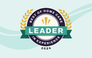 A circular badge with laurel leaves and the text "Best of Home Care - Leader in Experience 2024." The word "Leader" is prominently displayed on a green ribbon across the center of the badge. The background is light blue with a wave pattern.