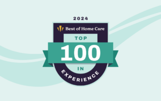 A badge reading "Best of Home Care - Top 100 in Experience 2024" on a teal and dark blue color scheme background. The design features a ribbon and shield motif with abstract wave lines in a soft blue color.
