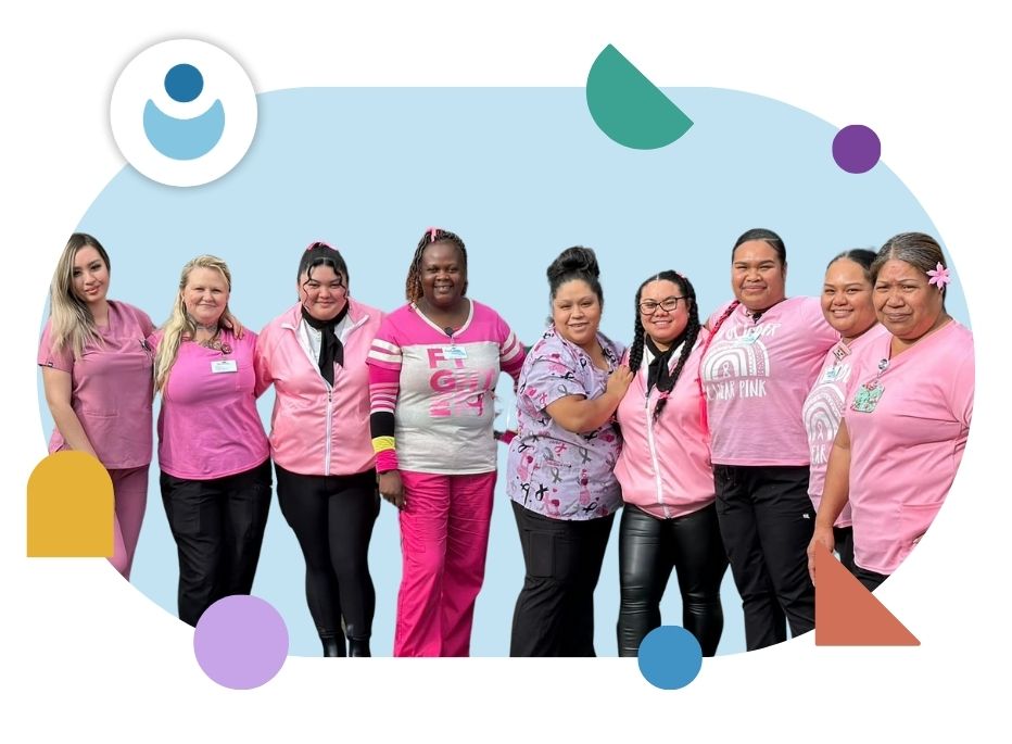 Hero Image_Cascade Senior Living A group of nine women stand together smiling, wearing various shades of pink and purple tops, against a blue background with colorful geometric shapes around the border.