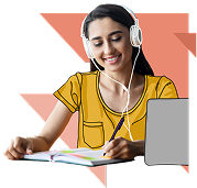 A young woman wearing headphones smiles while writing in a notebook and looking at a laptop.