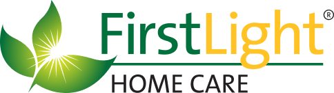 Logo for FirstLight Home Care featuring a stylized green and yellow leaf on the left, with "FirstLight" in green and yellow text and "Home Care" in smaller green text below.