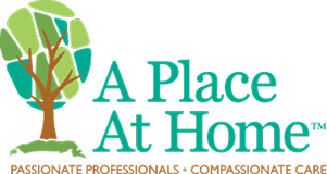 Logo for "A Place At Home" featuring a stylized tree and green text. Below, it reads "Passionate Professionals • Compassionate Care" in orange. The background is light gray.